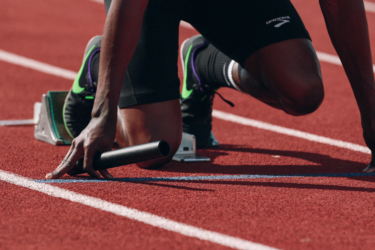 Athlète en position de départ dans les starting-blocks sur une piste