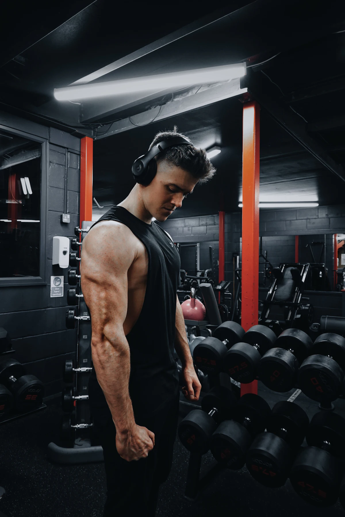 Homme concentré avec un casque audio, seul dans une salle de sport sombre