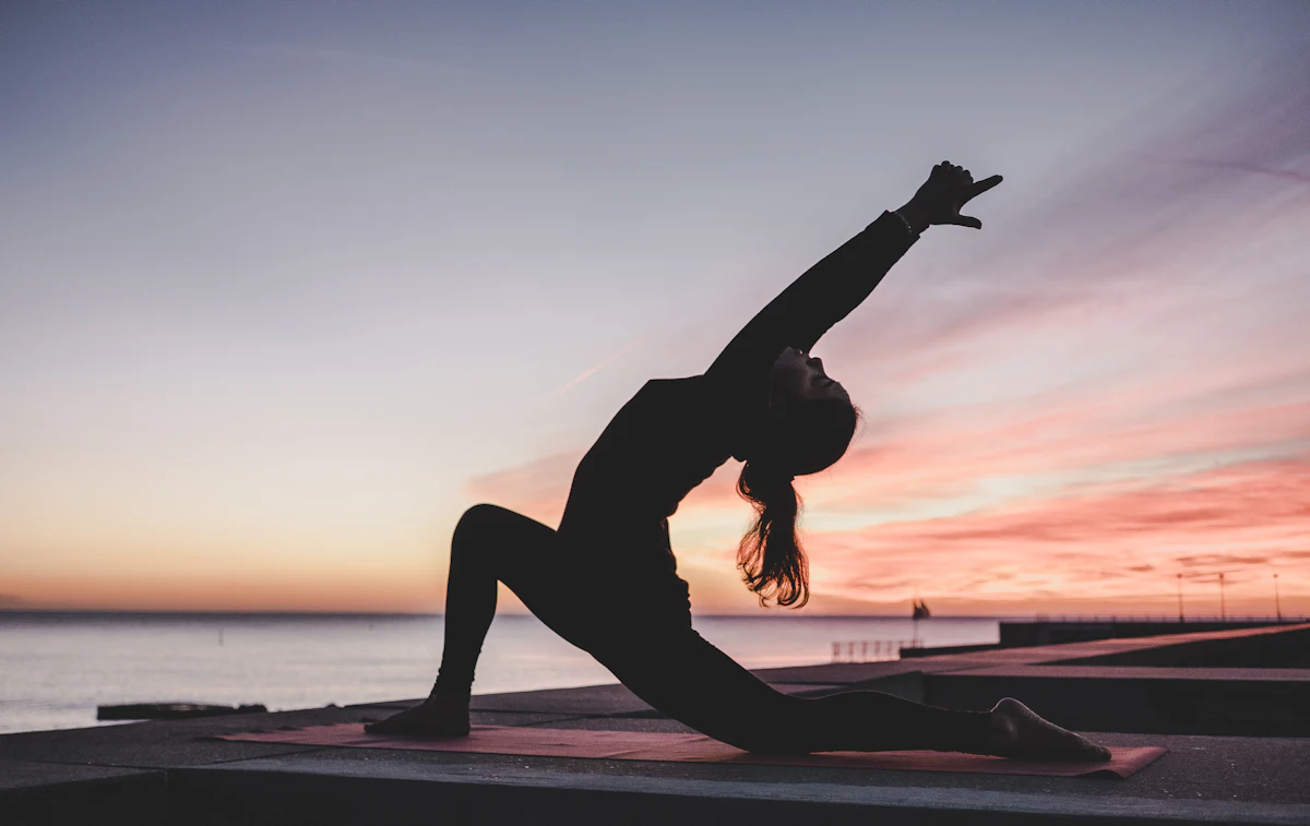 Silhouette en fente basse, bras tendu vers le ciel au coucher du soleil