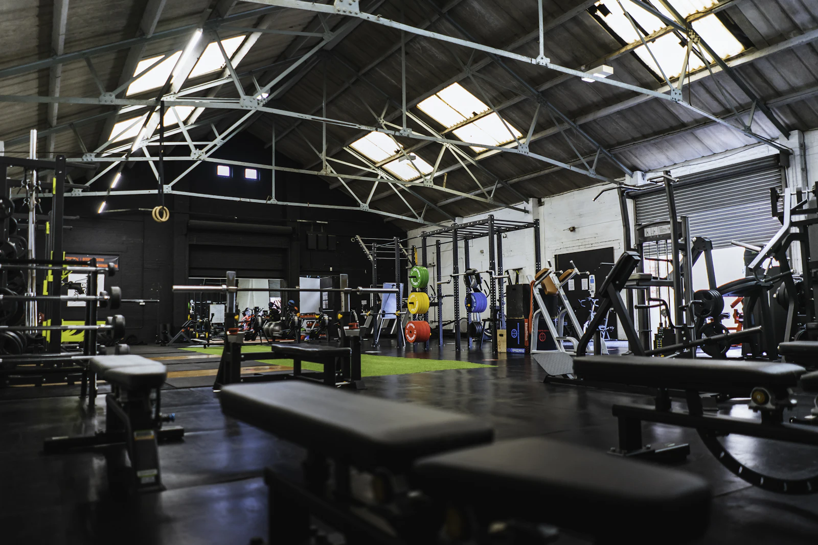 Grande salle d'entraînement lumineuse avec racks et bancs